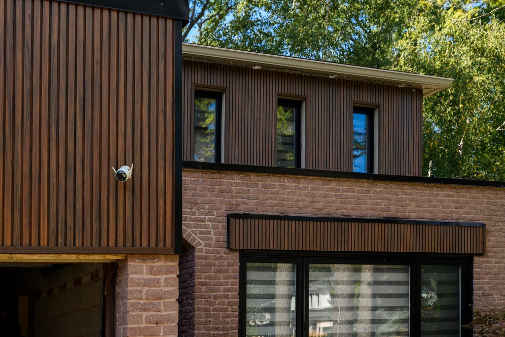 Wood-grain vertical siding on the upper floor of a brick house