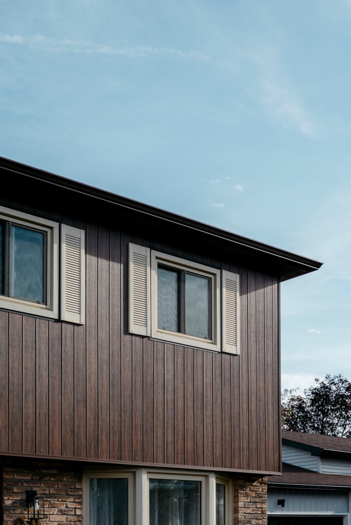 Upper storey clad in vertical wood-grain siding with white window trim