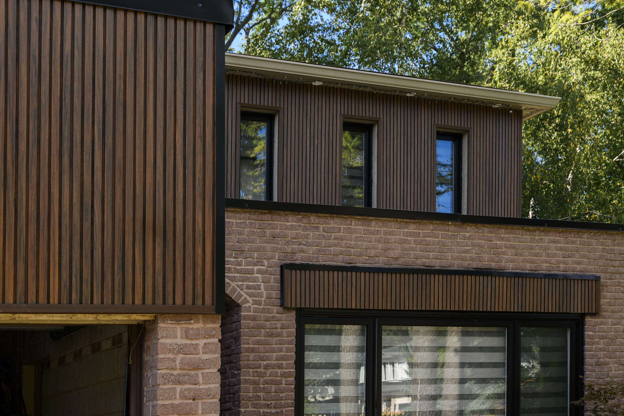 Vertical wood-grain siding on a brick home, installed by Karpi Renovations