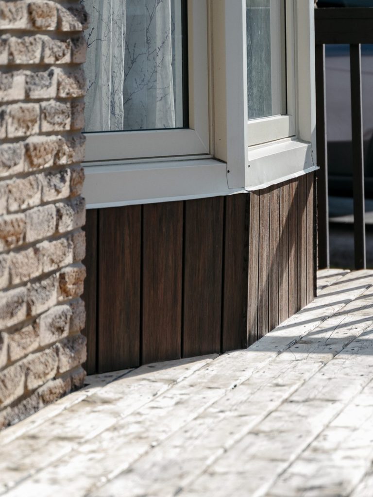 Wood-grain siding skirting beside a stone wall